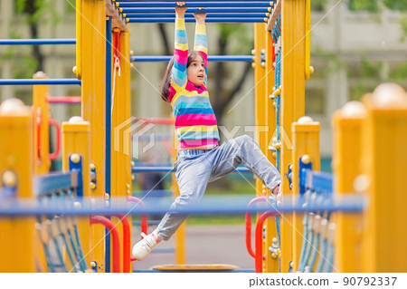 a little girl hangs on a childrens ladder on a bright playground in the park in summer 90792337