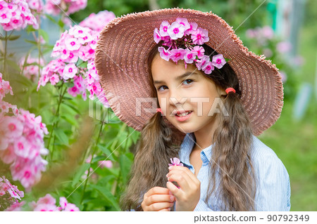 Portrait of a cute little girl in hat with pink flowers phlox Portrait of a cute little girl in hat with pink flowers phlox 90792349