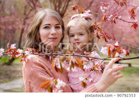 Portrait of mother and daughter in the park with blooming pink sakura Portrait of mother and daughter in the park with blooming pink sakura 90792353
