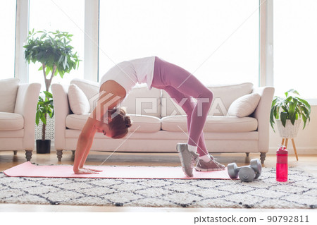Young adult fit woman doing arch exercise alone at home 90792811