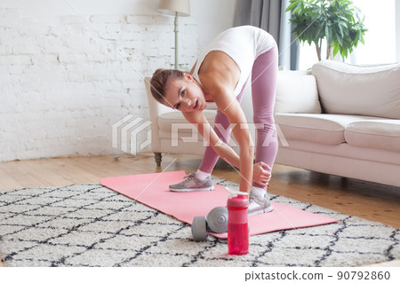Young sporty woman with dumbbells and bottle of water doing exercise. Healthy lifestyle concept 90792860