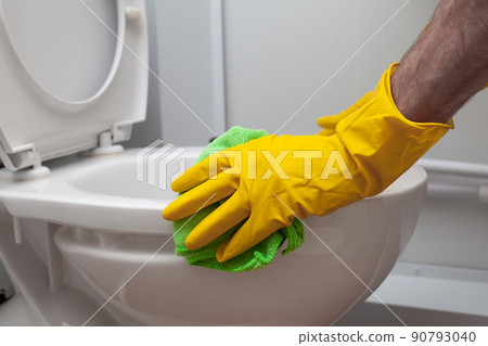 Man cleans a bathroom toilet with a green brush 90793040