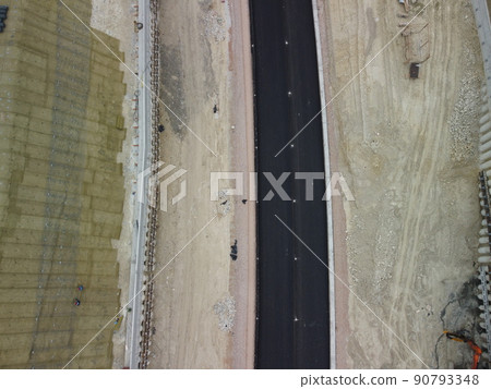 Workers reinforce the slope over the new road. Road construction in progress on slope nature canyon. Infrastructure development and logistics. Aerial drone shot 90793348