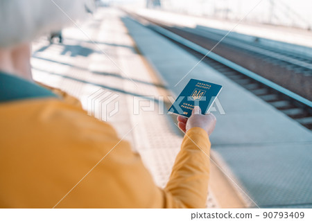 Woman hands with Ukrainian biometric passport id to travel the Europe without visas at trip train station. Modern passport with electronic chip let Ukrainians travel to European Union without visa 90793409