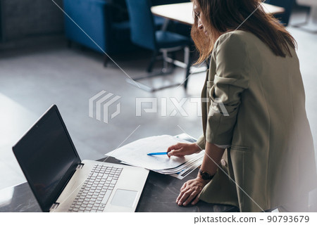 Woman stands at desk and looks through documents Woman stands at desk and looks through documents 90793679