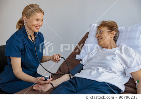 Female doctor therapist checking blood pressure of senior woman in the ward of modern clinic 90796235