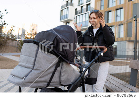 caring mom entertains her baby in a baby stroller 90798669