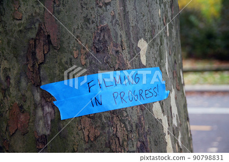 Filming in progress sign on a tree at the park 90798831