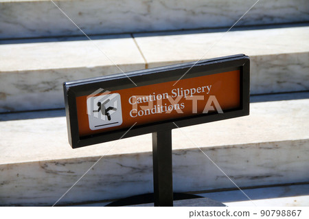 Caution, slippery conditions brown sign with icon representation on marble steps 90798867