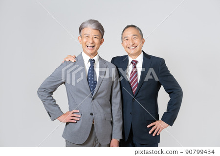 Portrait of two senior men wearing suits, crossing their shoulders and putting their hands on their hips 90799434