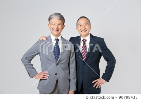 Portrait of two senior men wearing suits, crossing their shoulders and putting their hands on their hips Portrait of two senior men wearing suits, crossing their shoulders and putting their hands on their hips 90799435