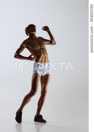 Contemp dance, performance. Young flexible shirtless man in underwear dancing isolated on gray background. Art, music, beauty. Healthy lifestyle concept Contemp dance, performance. Young flexible shirtless man in underwear dancing isolated on gray background. Art, music, beauty. Healthy lifestyle concept 90800399