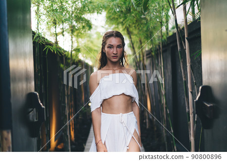 Young woman in white dress standing in garden 90800896