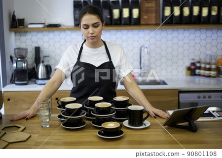 Skilled 20s woman in apron barista preparing cups of hot beverages working in coffee house 90801108