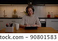 Happy girl in headphones works on a tablet in the living room and listens to music 90801583