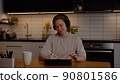 Teenage girl relaxes, listens to music with mp3 player in headphones at the table in the living room 90801586