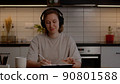 Teenage girl relaxes, listens to music with mp3 player in headphones at the table in the living room 90801588