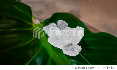 Crystal clear alum cubes or Potassium alum on green leaf. Chemical compound substance. Concept for beauty , spa and underarm treatment industrial.  90801719
