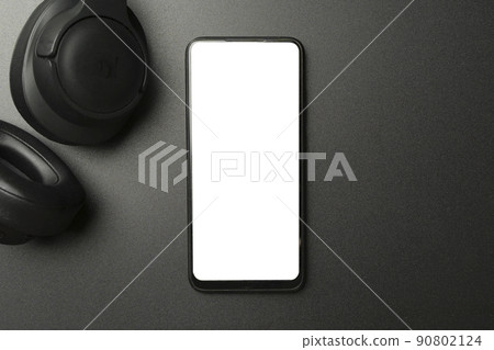 Headphones with smartphone with blank screen on black background. Music app, listening to audio, podcast concept. Headphones with smartphone with blank screen on black background. Music app, listening to audio, podcast concept. 90802124