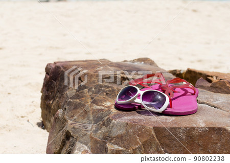 Pink flip flop shoes and Fashion sunglasses on the rock of beach. Summer Concept. Pink flip flop shoes and Fashion sunglasses on the rock of beach. Summer Concept. 90802238