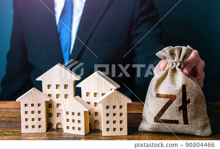 A businessman puts a polish zloty money bag near the houses. Construction industry, rental business and hotel tourism. Municipal budget of the city. Official. Investments in real estate assets. 90804466