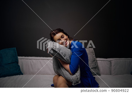 Beautiful woman with eyes closed sits on an art nouveau sofa and checks the pillow for softness, gently resting her head on the cushion. Healthy pleasant sleep and home interior design concept 90804922