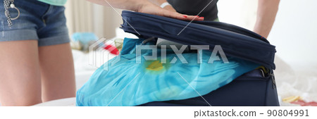 Man and woman trying to close suitcase with clothes closeup Man and woman trying to close suitcase with clothes closeup 90804991