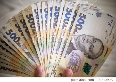 Money of Ukraine. Stack of ukrainian hryvnia banknotes in hands on wooden table. Hryvnia 1000 uah 90805629