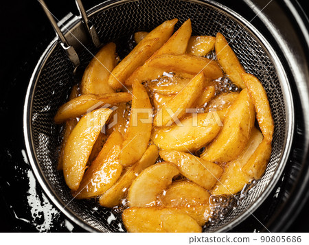 Cooking potatoes wedges in deep fryer 90805686