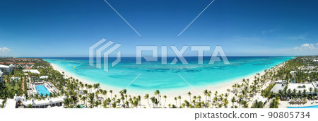 Bounty and pristine sandy shore with coconut palm trees, caribbean sea washes tropical coast. Arenda Gorda beach. Dominican Republic. Aerial panorama view Bounty and pristine sandy shore with coconut palm trees, caribbean sea washes tropical coast. Arenda Gorda beach. Dominican Republic. Aerial panorama view 90805734