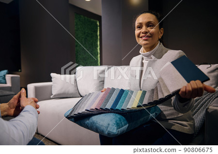 Confident pleasant African American woman, interior designer sales clerk in furniture store holding fabric samples for soft furniture upholstery Confident pleasant African American woman, interior designer sales clerk in furniture store holding fabric samples for soft furniture upholstery 90806675