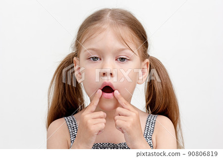 Child with open mouth and fingers on mouth corner 90806819