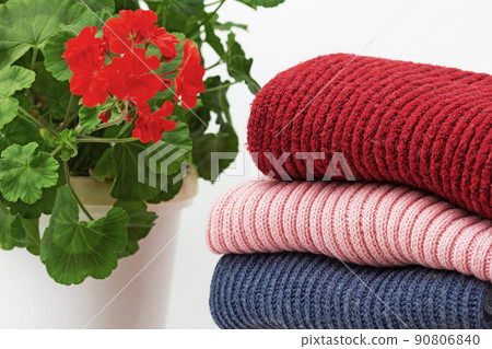 Stack of woolen clothes close to geranium Stack of woolen clothes close to geranium 90806840