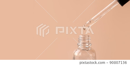 Pipette with transparent fluid hyaluronic acid or serum. Cosmetics, science and healthcare concept closeup. Dose of serum or retinol falls in a bottle. Front view. Beauty product presentation, macro Pipette with transparent fluid hyaluronic acid or serum. Cosmetics, science and healthcare concept closeup. Dose of serum or retinol falls in a bottle. Front view. Beauty product presentation, macro 90807136