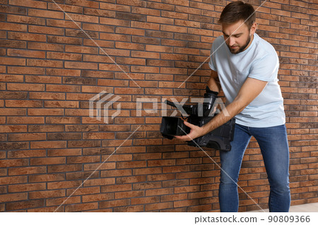 Operator with professional video camera near brick wall, space for text Operator with professional video camera near brick wall, space for text 90809366