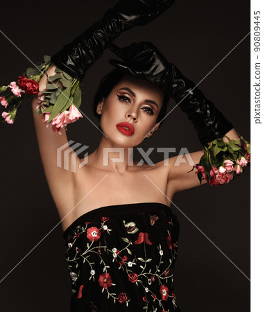 Beautiful brunette woman iwith a classic make-up, red lips, holding flowers. The beauty of the face. Beautiful brunette woman iwith a classic make-up, red lips, holding flowers. The beauty of the face. 90809445