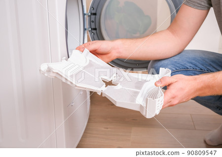 A man takes a lint filter out of dryer and cleans A man takes a lint filter out of dryer and cleans 90809547