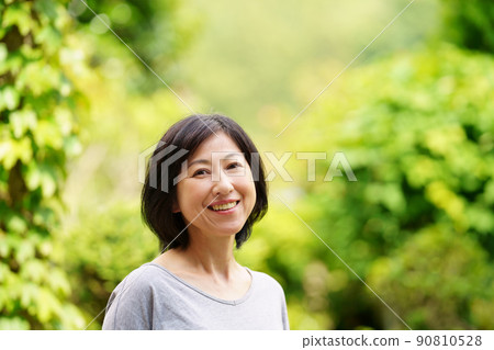 一位微笑著的中年婦女,身穿綠色 T 卹,看著鏡頭 一位微笑著的中年婦女,身穿綠色 T 卹,看著鏡頭 90810528