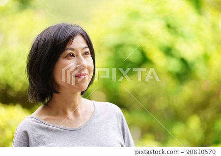 A smiling middle-aged woman wearing a T-shirt in the green A smiling middle-aged woman wearing a T-shirt in the green 90810570