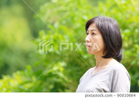 A middle-aged woman wearing a T-shirt in the green and standing lonely 90810664