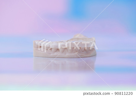Printed transparent dental cap made of polymer on a light colorful background. Dental splint against bruxism. Printed transparent dental cap made of polymer on a light colorful background. Dental splint against bruxism. 90811220