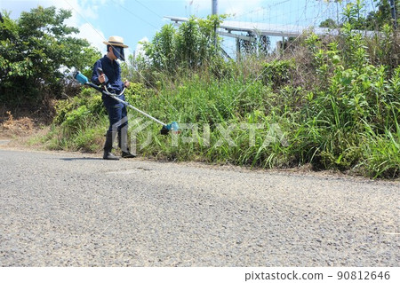 Weeding work along the road, a young man mowing grass Weeding work along the road, a young man mowing grass 90812646