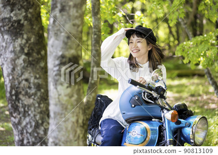 Bike girl image: A young woman straddling a motorcycle in the woods 90813109