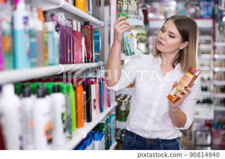 Woman looking for haircare cosmetics in shop 90814940
