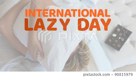 Digital composite image of caucasian woman hugging pillow with international lazy day text at home 90815979
