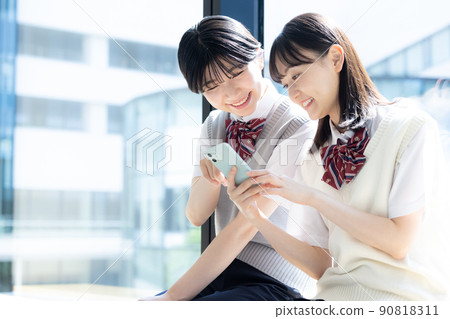 High school girls looking at smartphones, shooting cooperation "LINK FOREST" 90818311