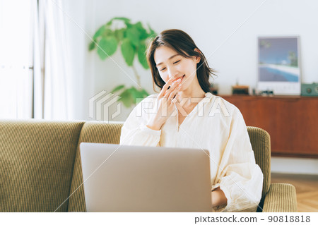 Woman using a computer on the sofa 90818818