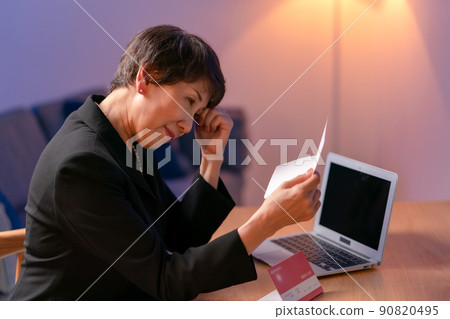 A woman wearing a mourning dress and looking at her passbook 90820495