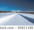 A straight snowy white road leading to a snowy mountain under the blue sky 90821386