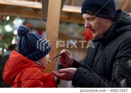caucasian man, father of little daughter feeding little girl at christmas market 90821987